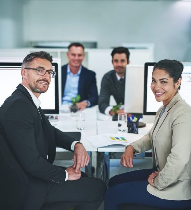 Portrait, business people and meeting for planning, computer and brainstorming for stock market. Face, group or employees with feedback, internet and review for proposal, smile or company development.
